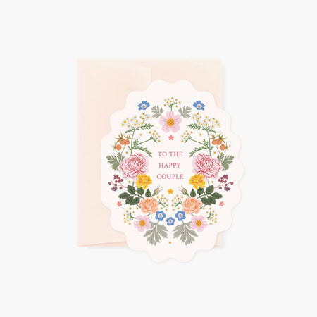 White card with scalloped edge with red text saying, “To the Happy Couple”. Images of a floral design border. A light pink envelope is included.