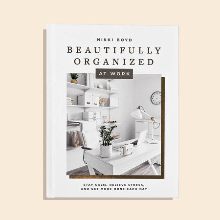 White cover with black text saying, “Beautifully Organized at Work Stay Calm, Relieve Stress, and Get More Done Each Day”. Images of a home office with white desk, white bookshelf and white office accessories.