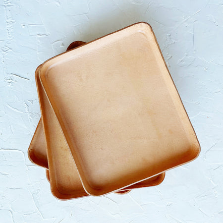 Rectangle light brown leather tray with rounded corners.