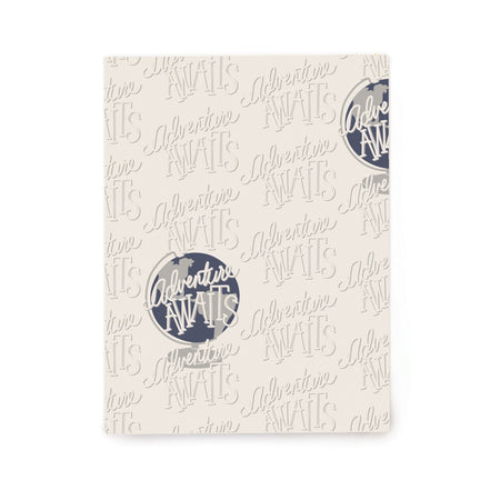 Ivory paper with silver text saying, “Adventure Awaits” tiled across paper. Images of a blue and silver globe saying, “Adventure Awaits” also scattered across paper. 