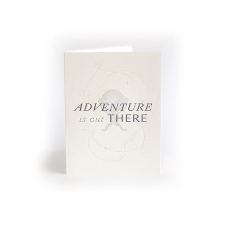 Ivory card with gray text saying, “Adventure is Out There”. Images of a gray stand up globe. An ivory envelope is included.