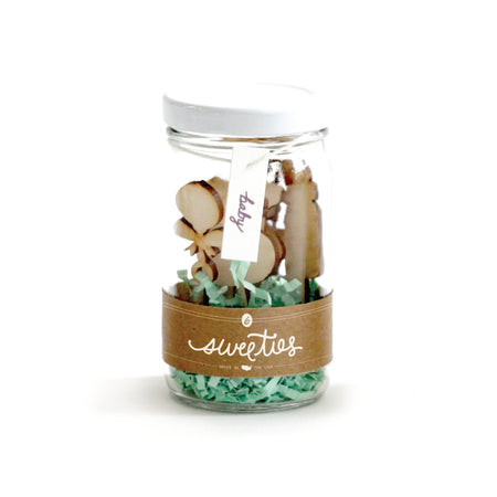 Wooden picks in the shapes of blocks, rattle, duck, onesie, bottle and pacifier. Packaged in a cylinder glass jar with teal stuffing and a gold label.