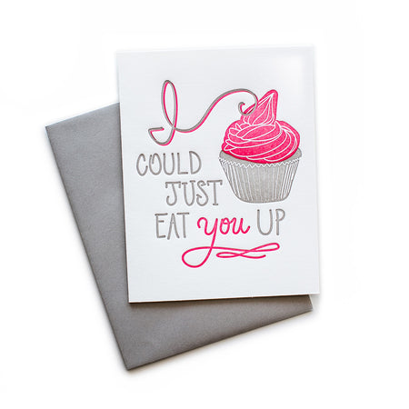 White card with gray and pink text saying, “I Could Just Eat You Up”. Image of a cupcake with pink swirling frosting. A gray envelope is included.