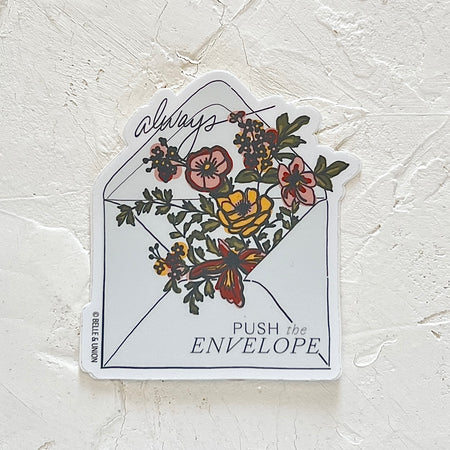 White sticker with image of a white envelope with colorful flowers and greenery coming out of the flap. Gray text saying, “Always Pushing the Envelope.” 