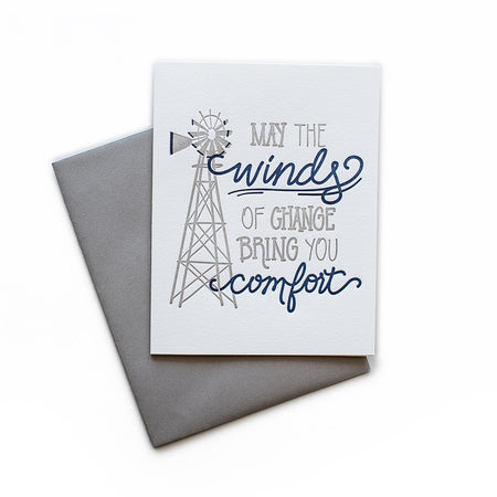 White card with gray and blue text saying, “May the Winds of Change Bring You Comfort”. Image of a large gray farm windmill. A gray envelope is included.