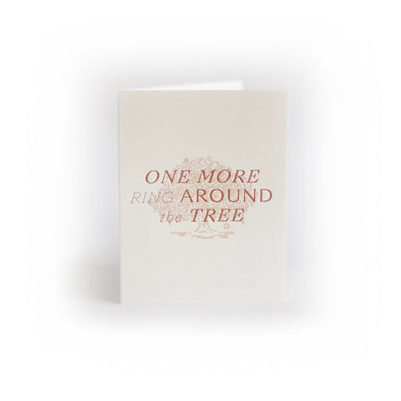 Ivory card with red text saying, “One More Ring Around the Tree”. Image of a great oak tree. An ivory envelope is included.