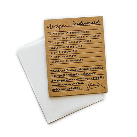Brown card with black and brown text saying, “Recipe for Bridesmaid: 1 fabulous formal dress; 1 pair of incredible shoes; unlimited bobby pins; 1 part supportive; 1 part assertive; lifetime of memories. Blend with care till personalities are well mixed. Accept imperfections among giggles, smiles and endless photos.” Image of bobby pins in bottom right corner. A white envelope is included.