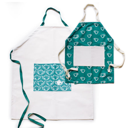 Two aprons: Ivory apron with teal waist straps and teal neck strap. Teal square in center of apron with images of white teapots. Teal apron with images of white teacups and ivory waist straps and ivory neck strap. Ivory square in center of apron.