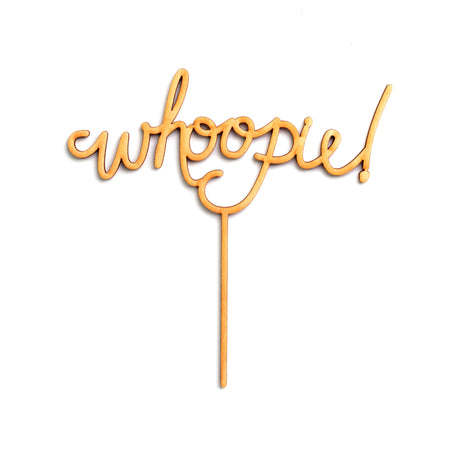 Wooden cut out cake topper in the image of text saying, “Whoopie!”