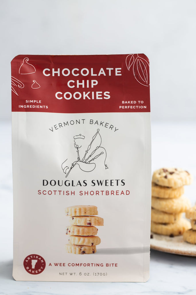 White package with brown border on top with white and black text saying, “Douglas Sweets Vermont Bakery Scottish Shortbreads Chocolate Chip Cookies”. Image of a stack of shortbread cookies and outline of a man playing bagpipes.