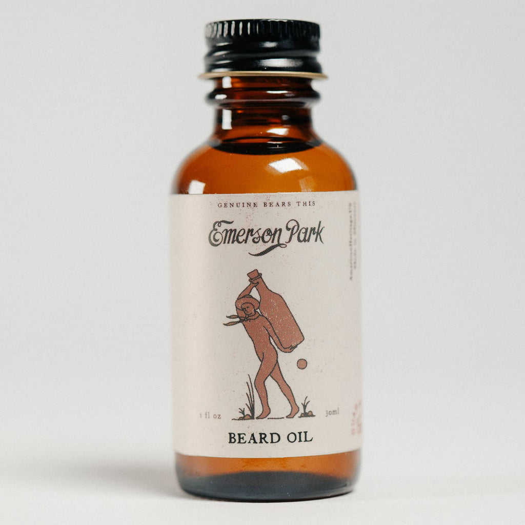Brown glass bottle with black lid and white label. Black text saying, “Emerson Park Beard Oil”. Image of a man carrying a bottle on his back.