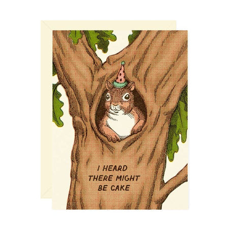 White card with images of a squirrel popping out of a hole in the center of a tree. Squirrel is wearing a birthday party hat. Black text saying, “I Heard There Might Be Cake”. A white envelope is included.