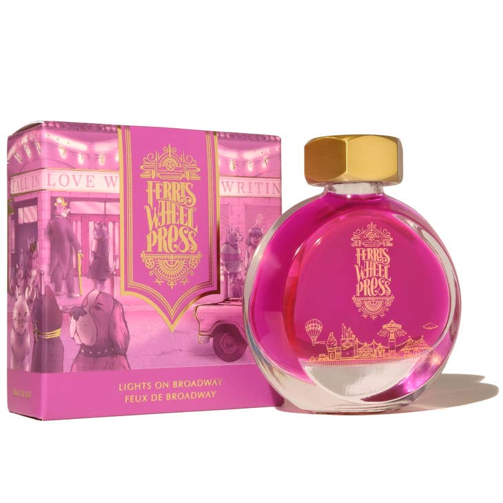 Round glass bottle with gold cover and gold text saying, "Ferris Wheel Press" with images of a carnival on front of bottle. Ink is magenta pink. Packaged in square pink box with images of a NYC street.