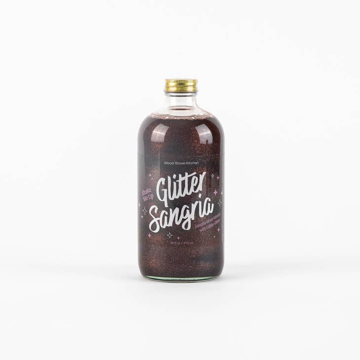 Glass bottle with gold cap and clear label with white text saying, "Glitter Sangria". Liquid is a brown color with silver glitter.