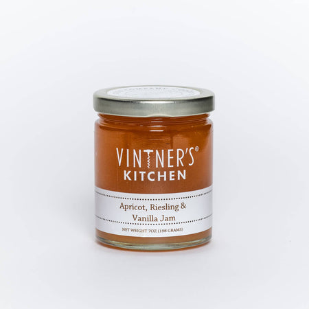 Glass jar with metal lid. White text saying, “Vintner’s Kitchen Apricot, Reisling & Vanilla Jam”.