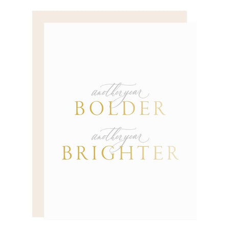 White card with gray and gold text saying, “Another Year Bolder Another Year Brighter”. A cream envelope is included.