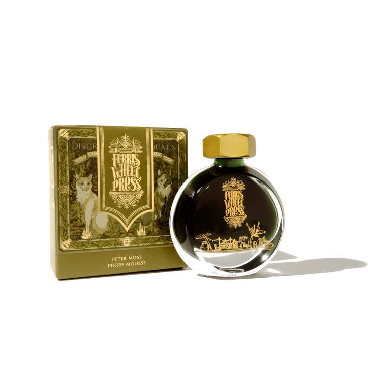Round glass bottle with gold cover and gold text saying, "Ferris Wheel Press" with images of a carnival on front of bottle. Ink is olive green. Packaged in square olive green box with images of foxes.