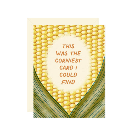 Card in the image of an ear of corn. Gold text saying, “This was the corniest card I could find”. A cream envelope is included.