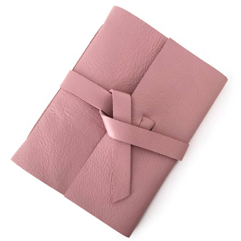 Blush Pink soft leather cover with two leather straps crossed in the middle.