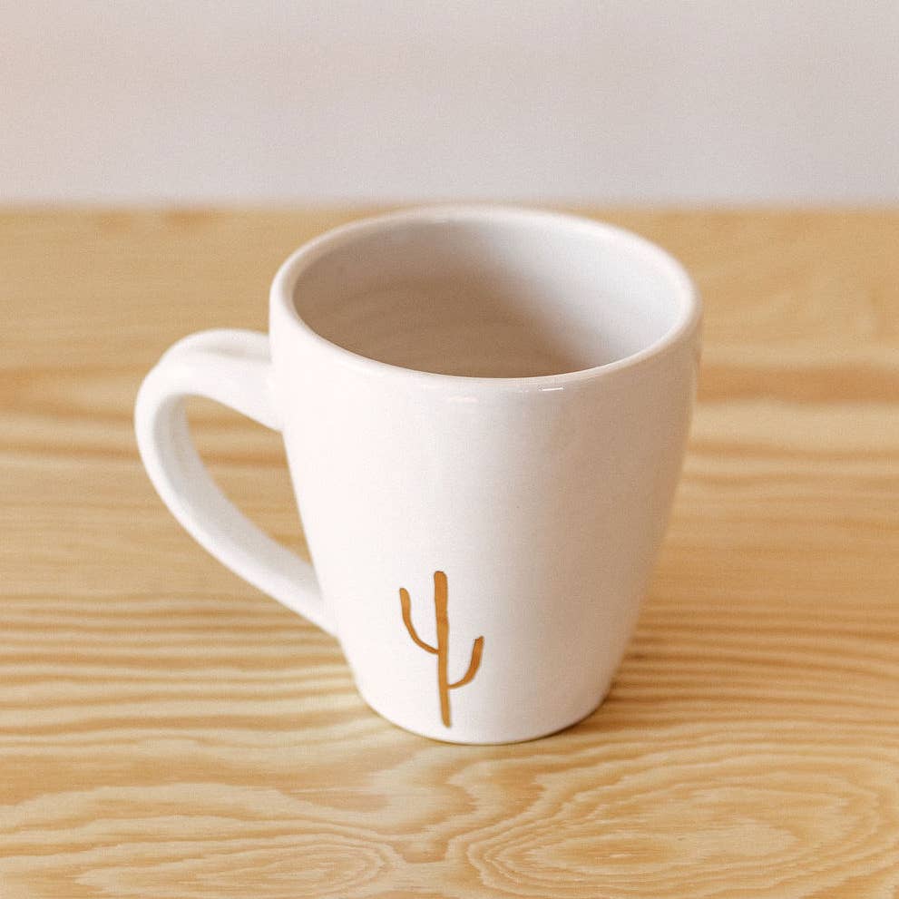 White ceramic mug with image of gold cactus in center bottom of mug.