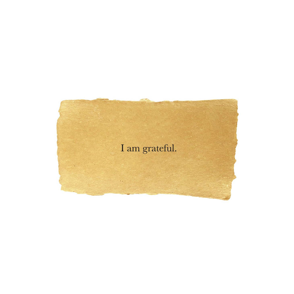 Tan rectangle with torn edges and black text saying, “I am Grateful”.