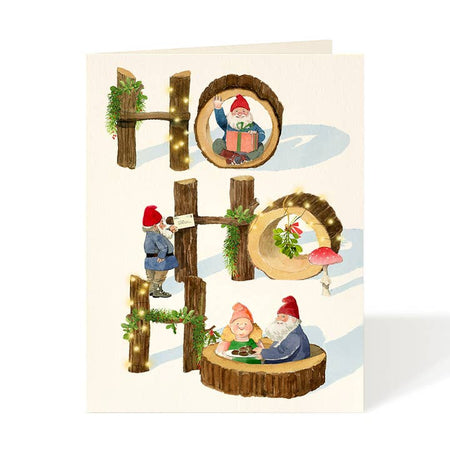 White Christmas card with gnomes and 'HO HO HO' text made of wooden logs. A white envelope is included.