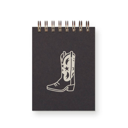 Black cover with silver foil image of a cowboy boot in center. Gold spiral coil across top.