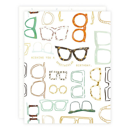 Ivory card with gold foil text saying, “Wishing You A Spectacular Birthday”. Images of several types of eyeglasses.  A white envelope is included.