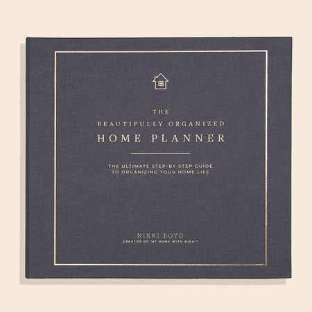 Black cover with gold foil text saying, “The Beautifully Organized Home Planner The Ultimate Step by Step Guide to Organizing Your Home Life”.
