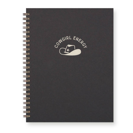 Black cover with silver foil text saying, “Cowgirl Energy” with image of a cowboy hat with a star in center. Metal coil binding on left side.