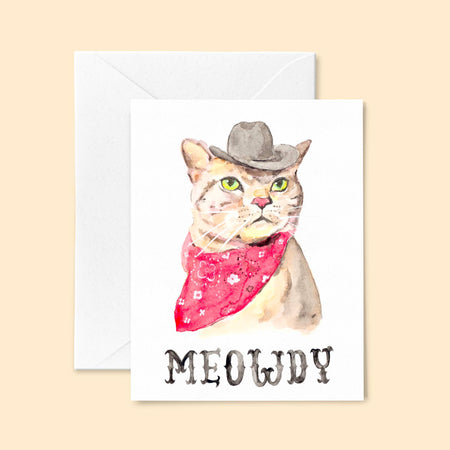 White card with image of a cat wearing a cowboy hat and a red bandana. Black text saying, “Meowdy”. A white envelope is included.