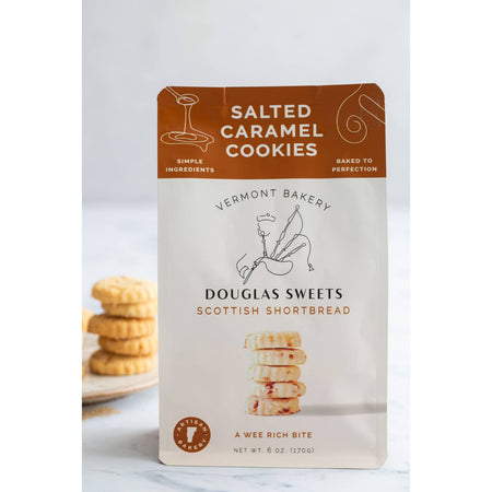White package with brown border on top with white and black text saying, “Douglas Sweets Vermont Bakery Scottish Shortbreads Salted Caramel Cookies”. Image of a stack of shortbread cookies and outline of a man playing bagpipes.