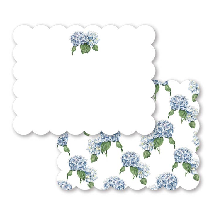 Set of two types of cards. One is white with scalloped edges with image of a blue hydrangea in top center. Other is white with scalloped edges with images of blue hydrangeas scattered across card. White envelopes are included.