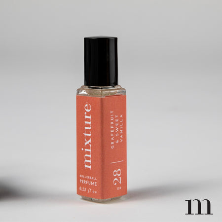 Small rectangular glass bottle with black lid. Orange label with white text saying, “Mixture Eau de Parfum”.