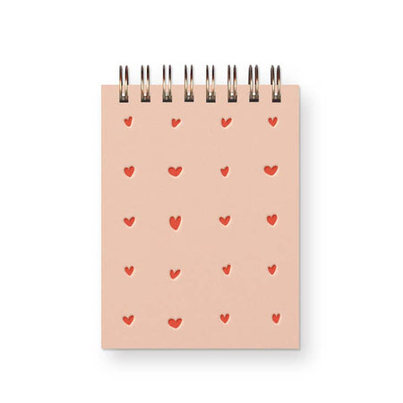 Notebook with pink cover and dark pink heart grid design. Metal coil binding across the top.
