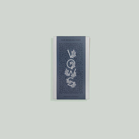 Vertical rectangular blue cover with silver foil text saying, “VOWS”. Lettering has floral accents on each side.