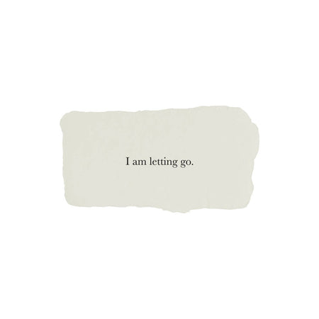 Ivory rectangle with torn edges and black text saying, “I am Letting Go”.