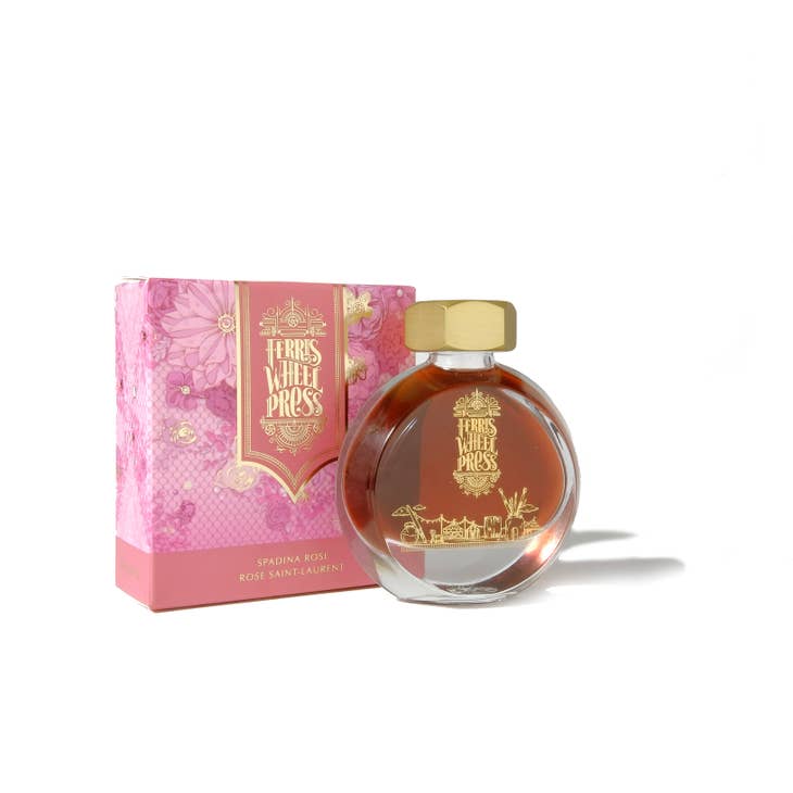 Round glass bottle with gold cover and gold text saying, "Ferris Wheel Press" with images of a carnival on front of bottle. Ink is pink. Packaged in square pink box with images of roses.