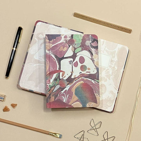 Hardcover journal with marble design including pink, purple, green, gray, tan and white colors.
