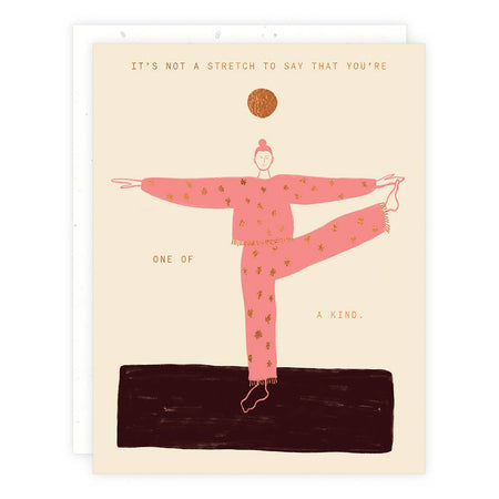Ivory card with gold foil text saying, “It’s Not A Stretch to Say That You’re One of A Kind”. Images of a woman doing yoga wearing a pink exercise suit standing on a brown mat.  A white envelope is included.