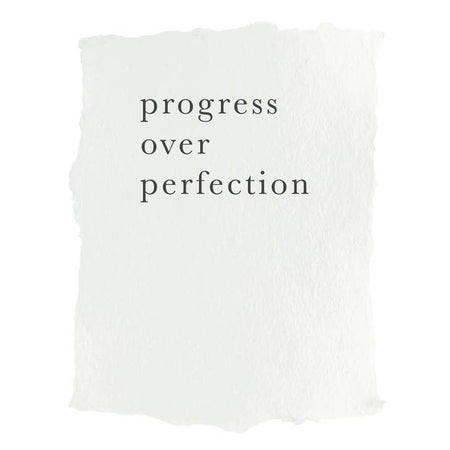 Art print on white paper with black text saying, “Progress Over Perfection”.