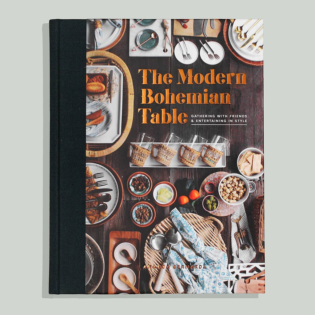Cover with images of a wooden dining table covered with various dining items such as: folded napkins, forks, spoons, food platters, and placemats. Orange text saying, “The Modern Bohemian Table”.