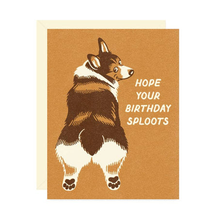 Brown card with the image of brown corgi dog with head turned sideways. White text saying, “Hope Your Birthday Sploots”.  A white envelope is included.
