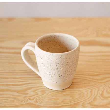 White and speckled tan ceramic mug with curved side handle.