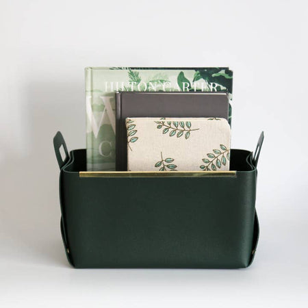 Dark green leather soft sided box with handles and gold metal strips along the two sides.