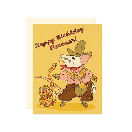 Yellow card with red text saying, “Happy Birthday Partner”. Image of a white mouse dressed as a cowboy and a birthday present with a yellow snake wrapped around it. A cream envelope is included.