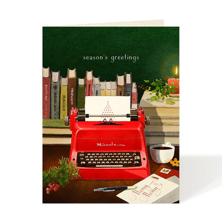Green card with image of vintage typewriter on a desk surrounded by books, a red candle and a cup of coffee. White text saying, “Season’s Greetings”. A white envelope is included.