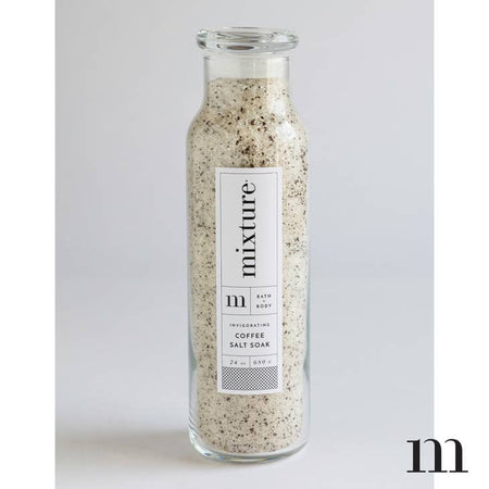 Coffee scented white and brown bath salt soak packaged in a tall glass bottle.