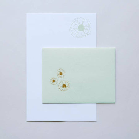 White paper with outline of a green flower in top right corner. Matching green envelopes with outline of gold flowers.