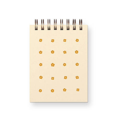 Notebook with ivory cover and orange flower grid design. Metal coil binding across the top.